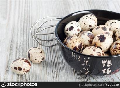 Quail eggs in a black dish on a wooden background.