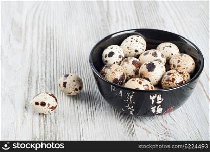 Quail eggs in a black dish on a wooden background.
