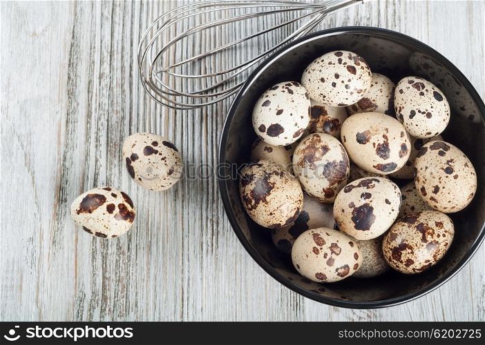 Quail eggs in a black dish on a wooden background. Top view.