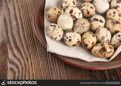 Quail eggs in a clay plate on a wooden background