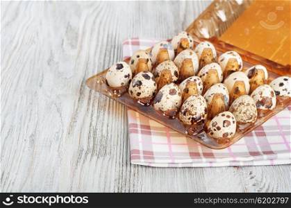 Quail eggs in a plastic box on a wooden background