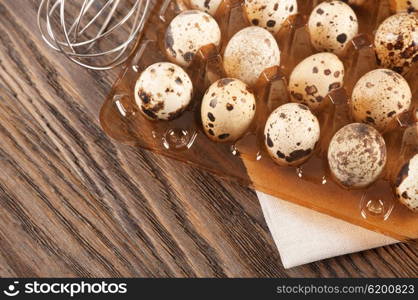 Quail eggs in a plastic container on a wooden background