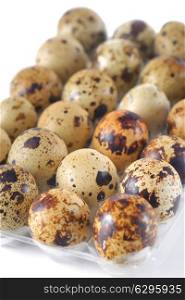 Quail eggs in a transparent plastic container on white background