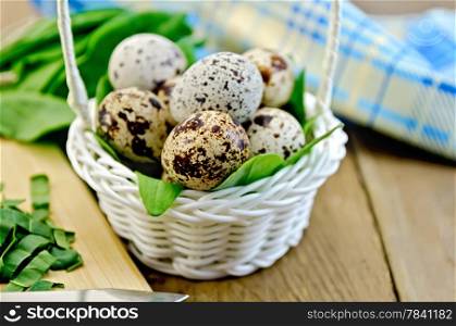 Quail eggs in a white wicker basket with sorrel, a napkin on the background of wooden boards