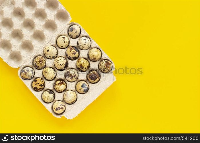 Quail eggs in cardboard box on yellow paper background. Template Top view Copy space lettering, text or your design.. Quail eggs in cardboard box on yellow paper background. Template Top view Copy space lettering, text or your design