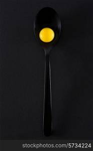 Quail eggs in spoon on black background