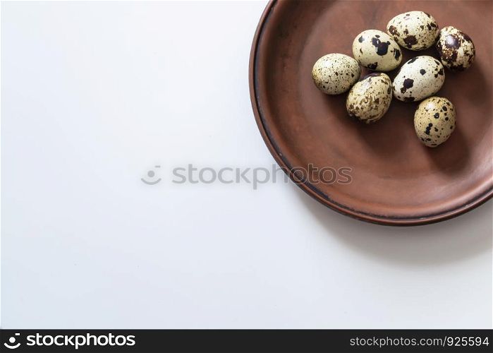 Quail eggs on clay plate on white background. Closeup photo