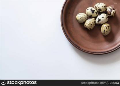 Quail eggs on clay plate on white background. Closeup photo