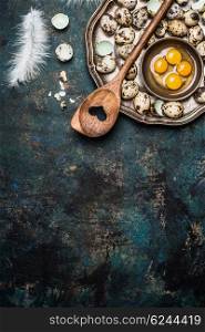 Quail eggs with cooking spoon on rustic background, top view. Broken quail egg.