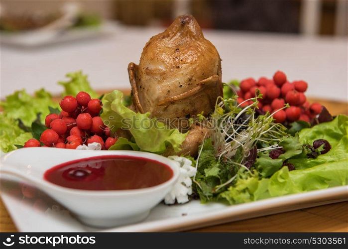 quail roasted with sweet and sour cranberry sauce decorated with rowanberry. quail roasted with sweet and sour cranberry sauce