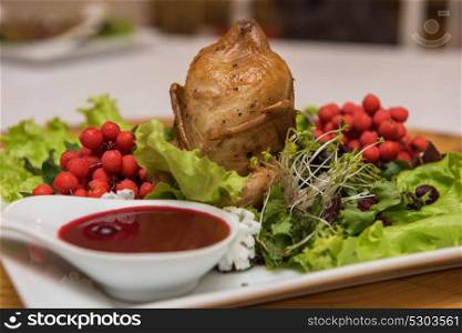 quail roasted with sweet and sour cranberry sauce decorated with rowanberry. quail roasted with sweet and sour cranberry sauce