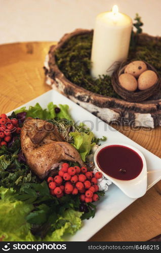 quail roasted with sweet and sour cranberry sauce decorated with rowanberry. quail roasted with sweet and sour cranberry sauce