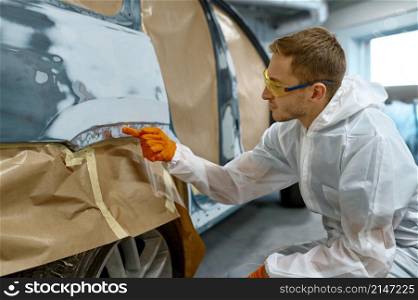 Quality control in car service. Repairman checking finished work. Old paint removing and priming. Repairman checking quality of old paint removal