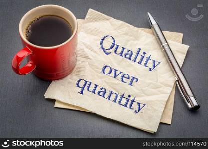 quality over quantity inspirational reminder note - handwriting on a napkin with cup of coffee against gray slate stone background