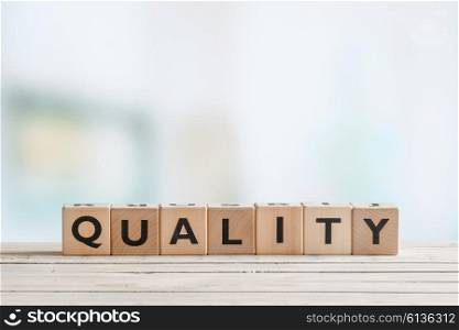 Quality sign on a wooden table on bright background