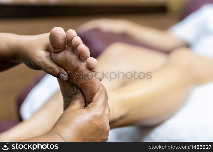Quarantine asian woman do foot massage at home while city lockdown for social distance due to coronavirus pandemic. Massage and spa is one of service business that shutdown while city lockdown.