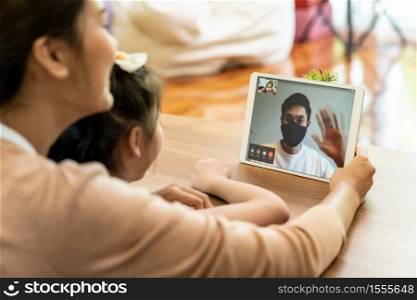 Quarantine father video conference call with his family of mom and daughter while stay in state quaratine. Technology and family reunion new normal while coronavirus covid-19 pandemic.