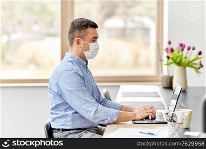 quarantine, remote job and pandemic concept - middle-aged man wearing face protective medical mask for protection from virus disease with laptop computer working at home office. man in mask with laptop working at home office