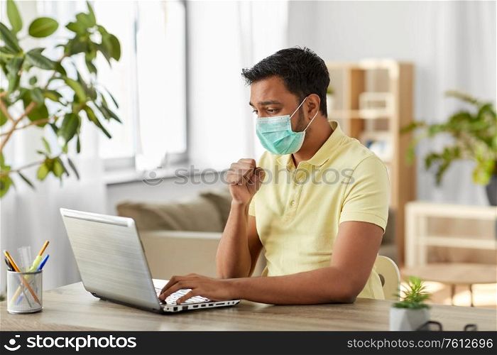 quarantine, remote job and pandemic concept - sick indian man wearing face protective medical mask for protection from virus disease with laptop computer working at home office and coughing. sick indian man in mask with laptop works at home