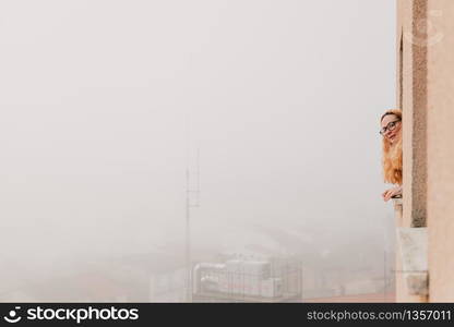 Quarantined woman bending over the window watching outside