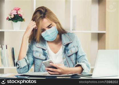 Quarantined woman working at home wearing face mask protect from Coronavirus. Concept of social distancing to stop spreading of Coronavirus Disease or COVID-19.