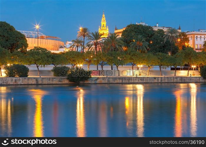 Quay of the river Guadalquivir, Famous Bell Tower named Giralda and Maestranza during evening blue hour, Seville, Andalusia, Spain