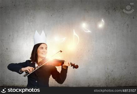 Queen of performance. Young pretty businesswoman in paper crown playing violin