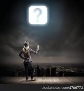 Question concept. Young woman in casual holding balloon shaped like question mark