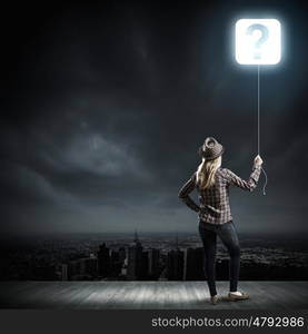 Question concept. Young woman in casual holding balloon shaped like question mark