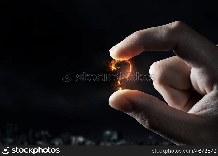 Question mark holden with fingers. Close view of hand holding question mark between fingers