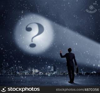 Question mark in spotlight. Businessman standing with back and looking at question mark concept