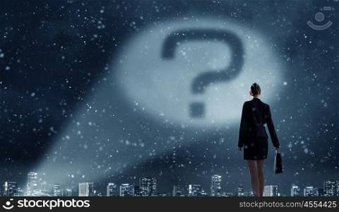 Question mark in spotlight. Businesswoman standing with back and looking at question mark concept