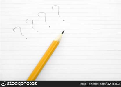 question mark written on paper by a yellow pencil