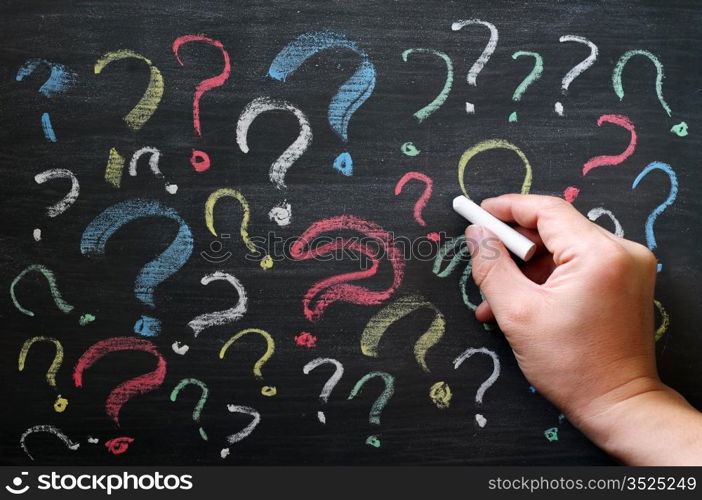 Question marks on chalkboard. Decision, confusion, FAQ or other concept. Hand writing with chalk on school black board.