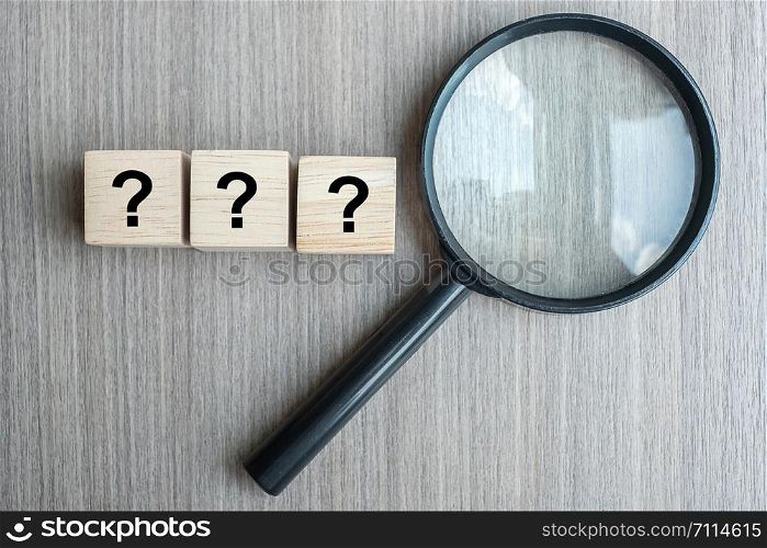 Questions Mark ( ? ) word with wooden cube block and magnifying glass on table background. SEO, vision, Idea, Strategy, Analysis, goals FAQ, Answer, Q&A and Information concept