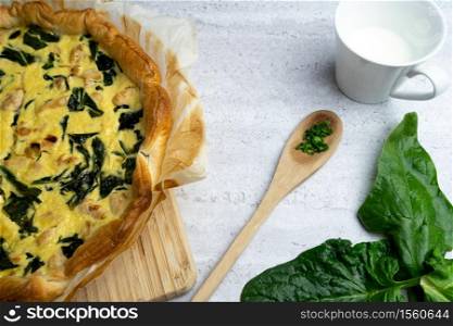 Quiche filled with chicken, chard with wooden spoon on soft background