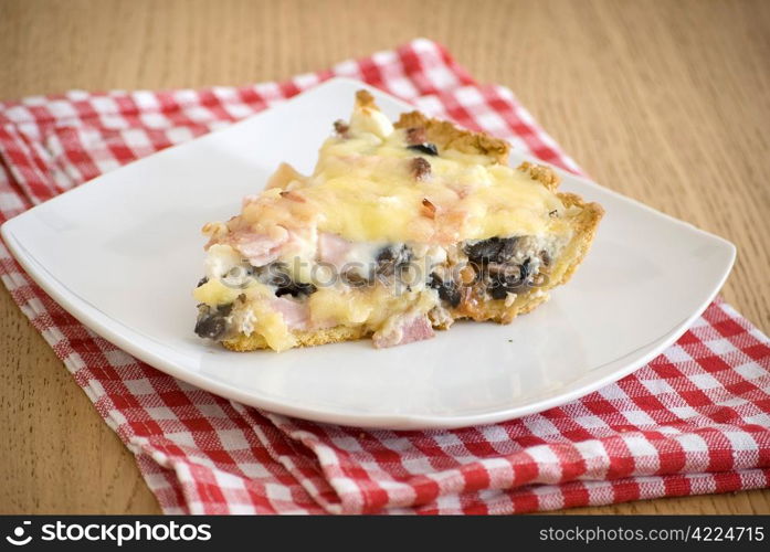 quiche with ham cheese salami muchrooms beans eggs in a white plate