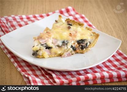 quiche with ham cheese salami muchrooms beans eggs in a white plate