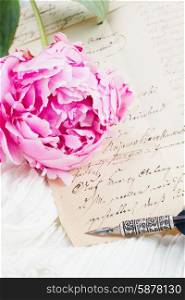 quill pen and antique letters. Pink peony with antique letter and feather pen on white lace background