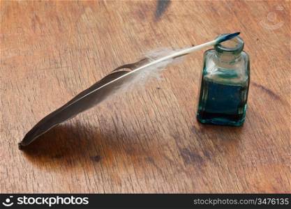 quill pen in a glass inkwell on a wooden table