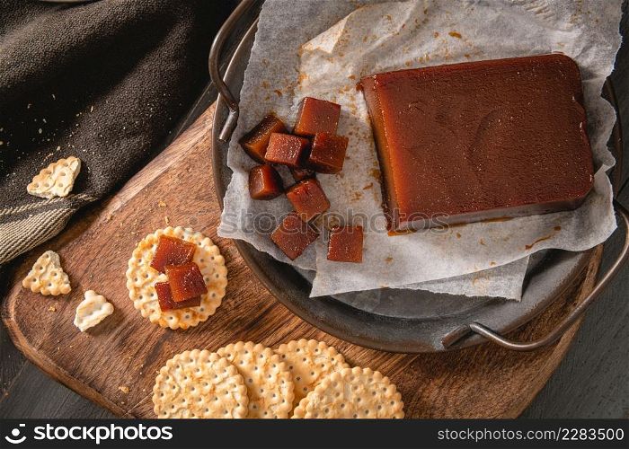 Quince cheese or marmelada is a sweet, thick jelly made of the pulp of the quince fruit. Marmalade in crackers on a kitchen counter. Dulce de membrillo in Spain