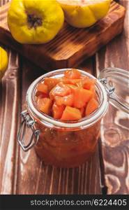 Quince jam in the glass jar and fruits on the background. Quince jam jar
