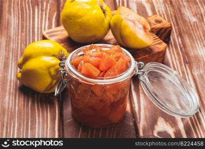 Quince jam in the glass jar and fruits on the background. Quince jam jar
