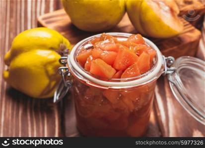 Quince jam in the glass jar and fruits on the background. The Quince jam