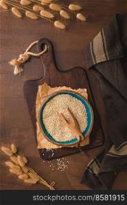Quinoa in ceramic bowl with wooden scoop on rustic countertop.
