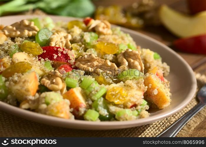 Quinoa Waldorf Salad with apple, celery, yellow raisins and walnut served on plate, ingredients in the back, photographed with natural light (Selective Focus, Focus in the middle of the salad)