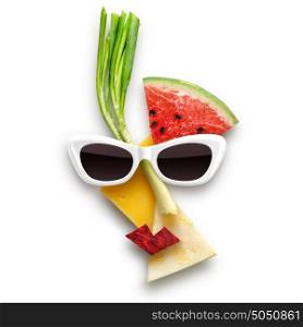 Quirky food concept of cubist style female face in sunglasses made of fruits and vegetables, isolated on white.