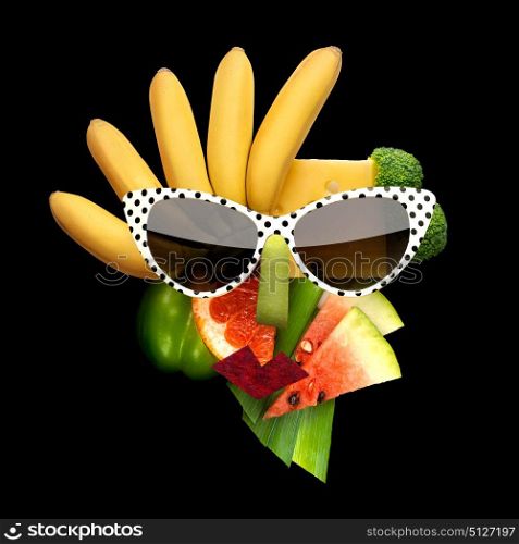 Quirky food concept of cubist style female face in sunglasses made of fruits and vegetables, on black background.