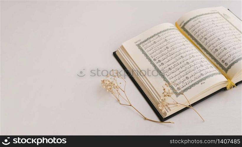 Quran book on table with candle beside