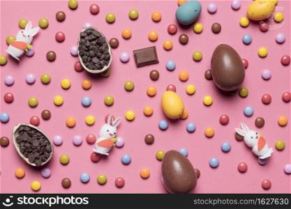 rabbit figurines easter eggs multicolored gems pink background